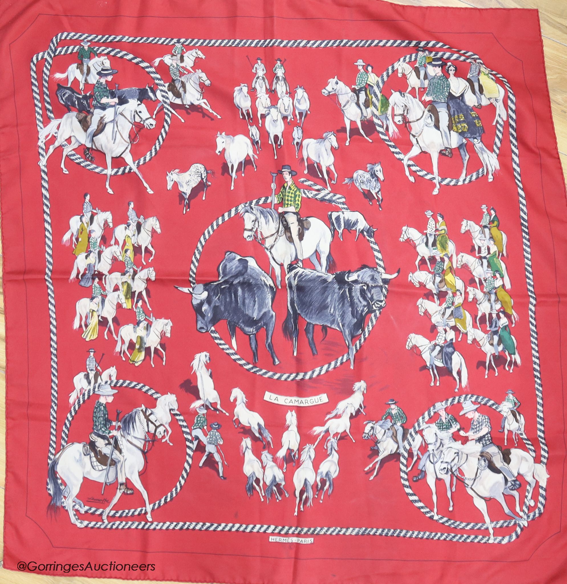 Three vintage Hermes silk scarves, 'Caparacons' (white ground), 'La Camargue' (red ground), and 'Ludovicus Magnus' (blue ground)